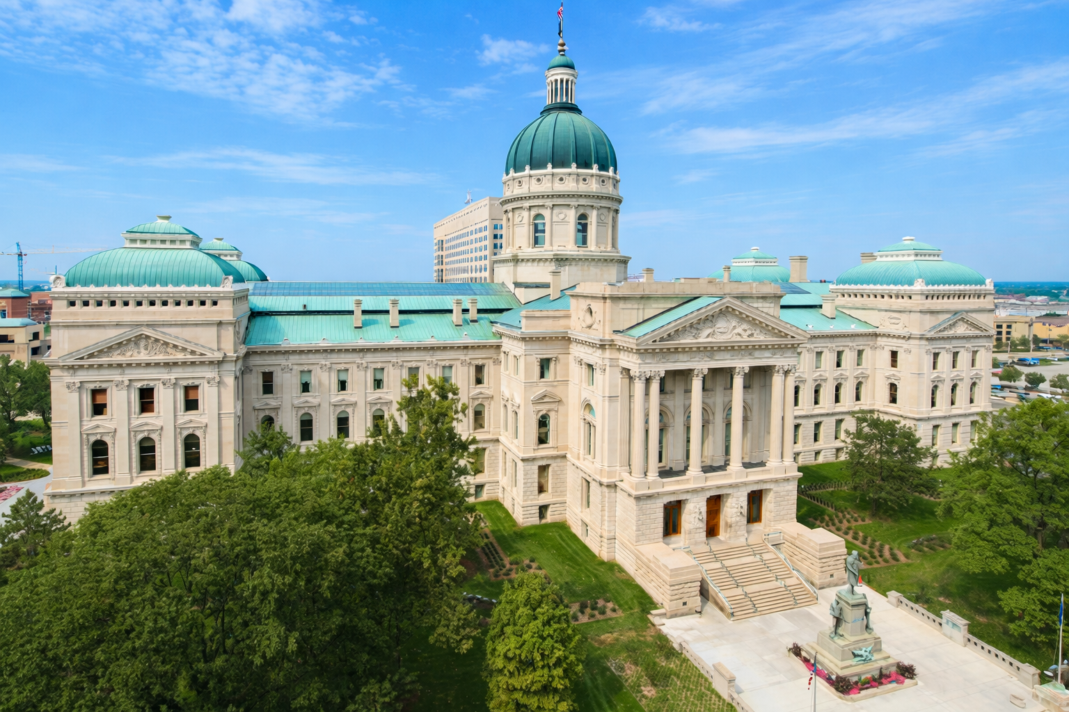 Indiana Statehouse in Indianapolis featuring neoclassical architecture and green copper dome under clear blue sky.